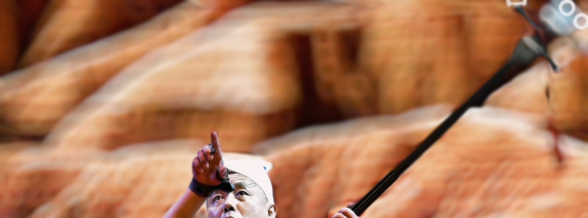 藝人著白衣紅帶，持傳統絃樂器表演，神情投入，背景似黃土風貌，盡顯民間藝術韻味