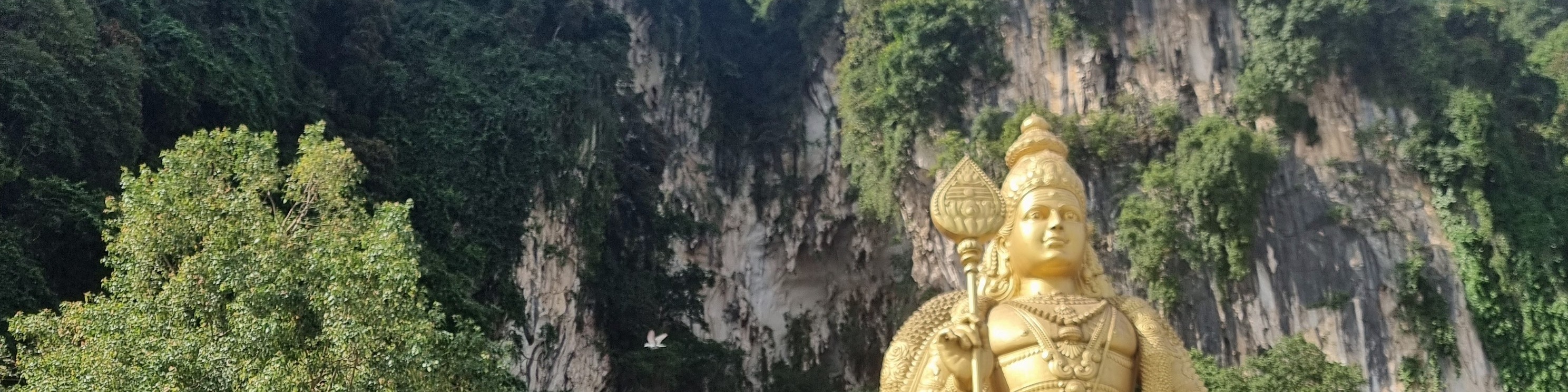 Majestic Batu Caves with towering cliffs and a golden Murugan statue