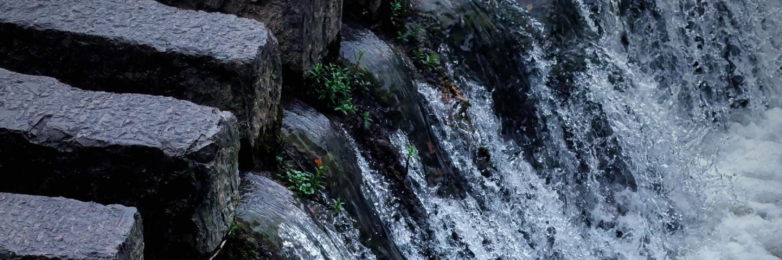 奔湧的水流順著層層石階傾瀉而下，撞出細碎的白色浪花，像無數條銀鏈在石縫間奔湧跳躍。深色的石階與清透的水流形成強烈的對比，把水的靈動與力量感展現得淋漓盡致，彷彿能聽見瀑布嘩嘩的聲響，撲面而來都是鮮活的自然氣息