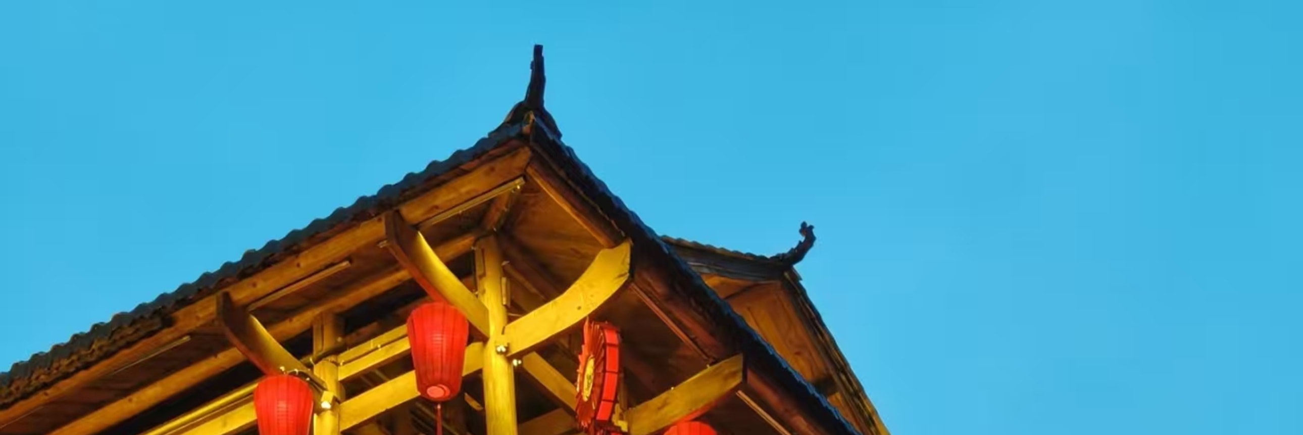 暮色漸濃時，這座三層木樓被紅燈籠與暖黃燈光點亮，層層疊疊的雕花欄杆與木樑在夜色裡格外醒目