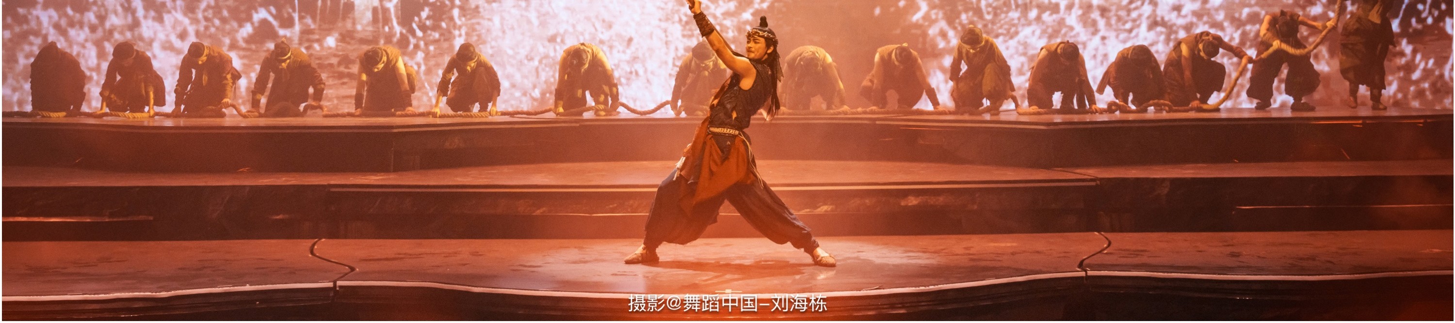 舞者手持道具,在水花四濺的震撼背景前,周圍眾多舞者以整齊的姿態配合,重現一場遠古治水的壯闊場景。 舞者手持道具,在水花四濺的震撼背景前,周圍眾多舞者以整齊的姿態配合,重現一場遠古治水的壯闊場景。