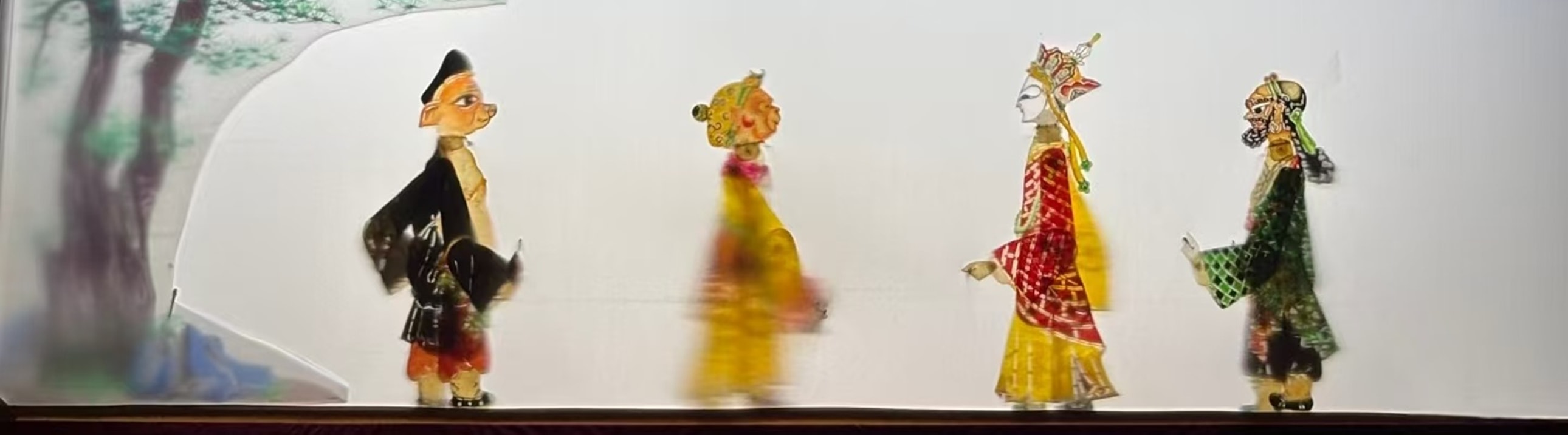 皮影戲舞臺上，師徒四人（悟空、八戒等）造型鮮明，背景是山水林景，盡顯皮影戲的傳統藝術特色