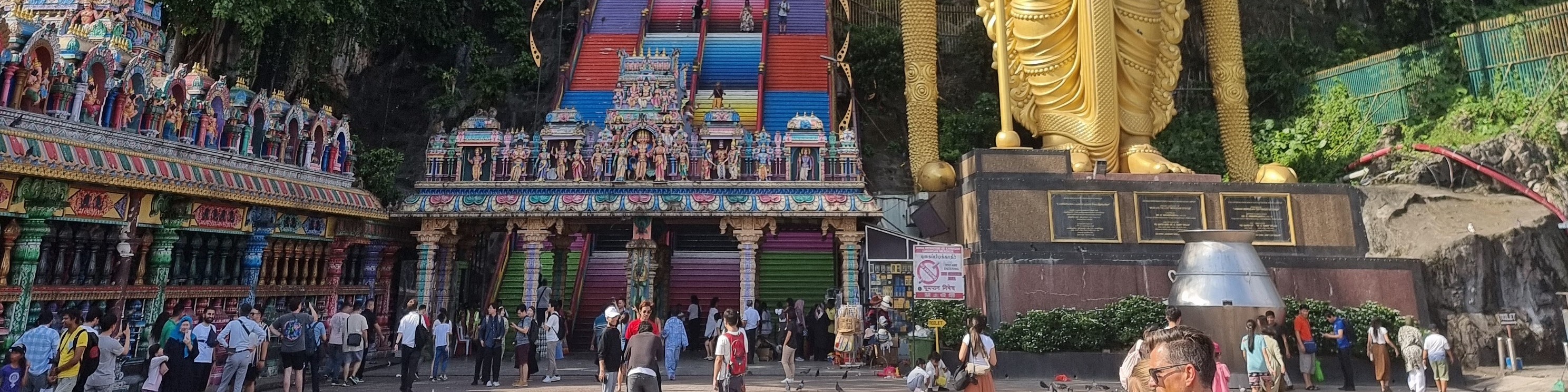 Majestic Batu Caves with towering cliffs and a golden Murugan statue