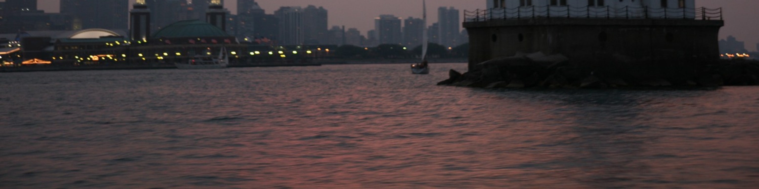 Admire Chicago Harbor Lighthouse glowing beautifully against the colorful evening sunset skies