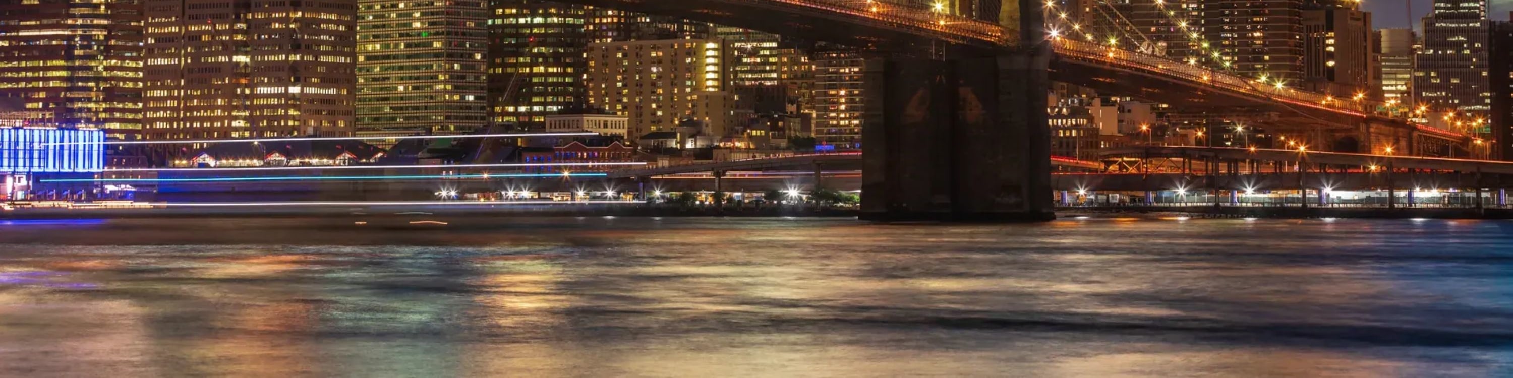 Iconic view of the Brooklyn Bridge glowing under city lights against the night sky