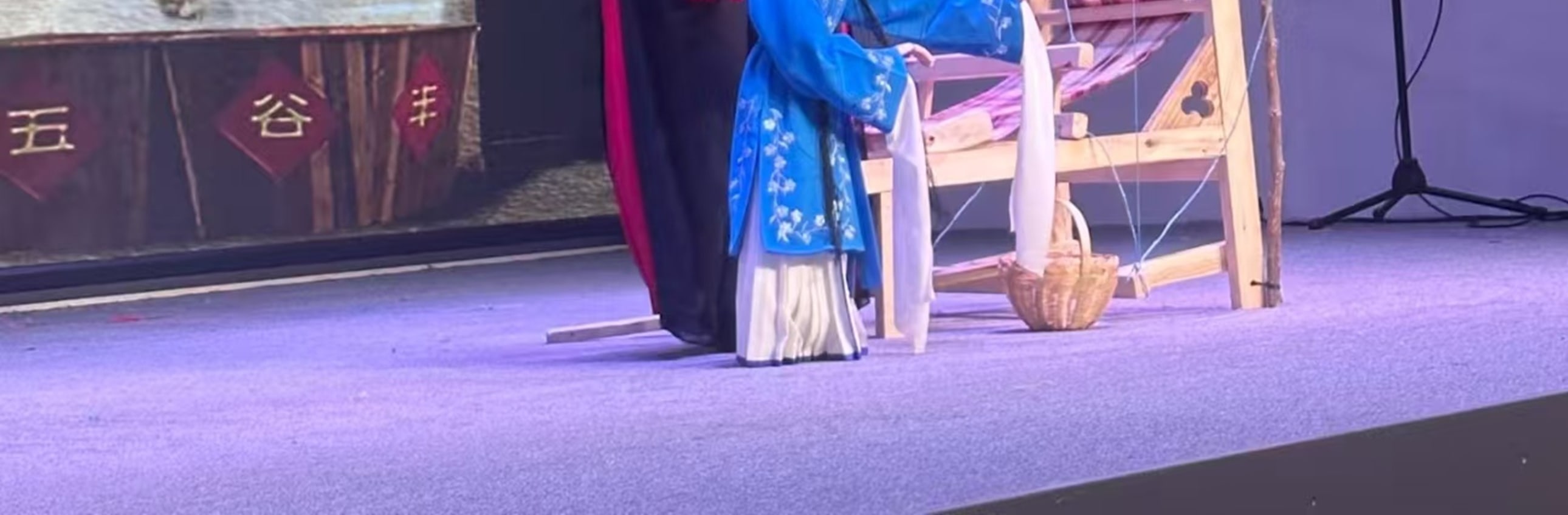 藍袍提線木偶動作活潑，手持小道具，衣飾精緻，背景是山水佈景