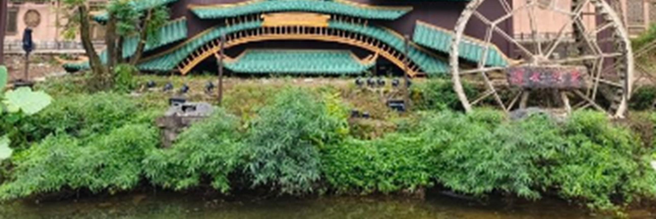 巨大的崖壁如刀削斧鑿，成為天然的背景板。青瓦飛簷的舞臺依水而建，層疊的屋頂如波浪般起伏，與旁邊吱呀轉動的水車相映成趣
