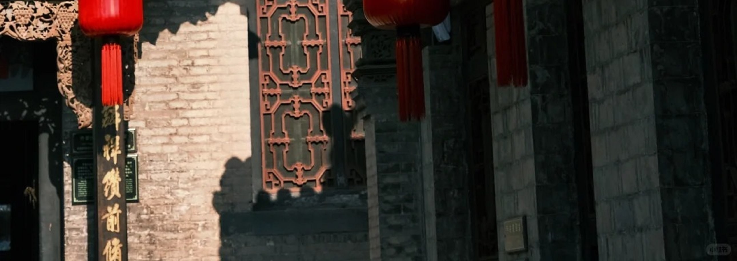 古建屋簷下紅燈籠高掛，雕樑畫棟細節精緻，紅灰色調交織，盡顯中式古建築的典雅韻味與傳統風情