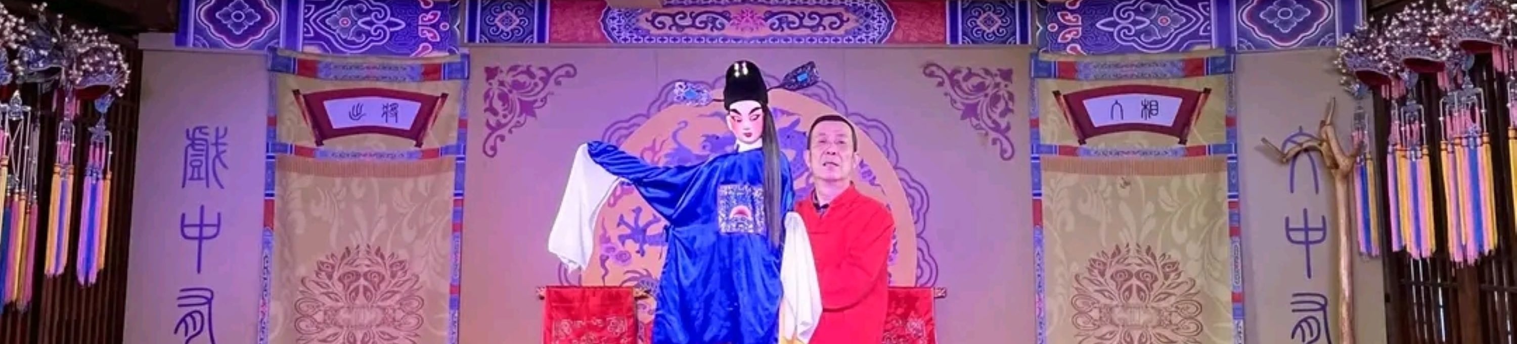 表演者手持身著藍色官服的木偶,木偶造型細膩,服飾具有戲曲特色 表演者手持身著藍色官服的木偶,木偶造型細膩,服飾具有戲曲特色