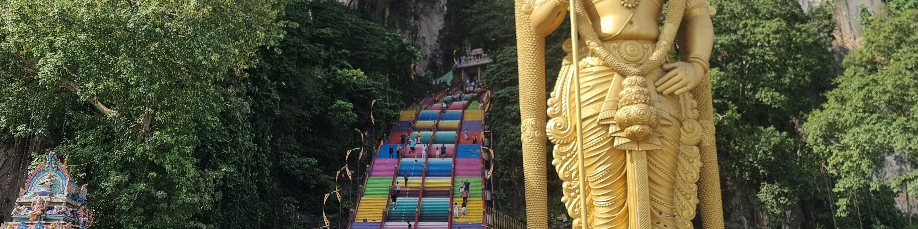 Majestic Batu Caves with towering cliffs and a golden Murugan statue