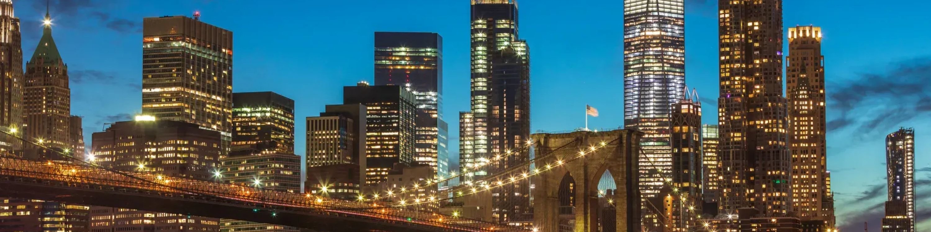 Iconic view of the Brooklyn Bridge glowing under city lights against the night sky