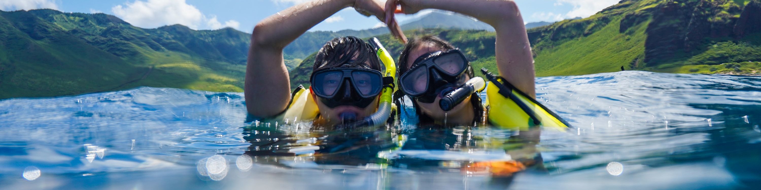 情侶在海中漂浮，用手比出愛心