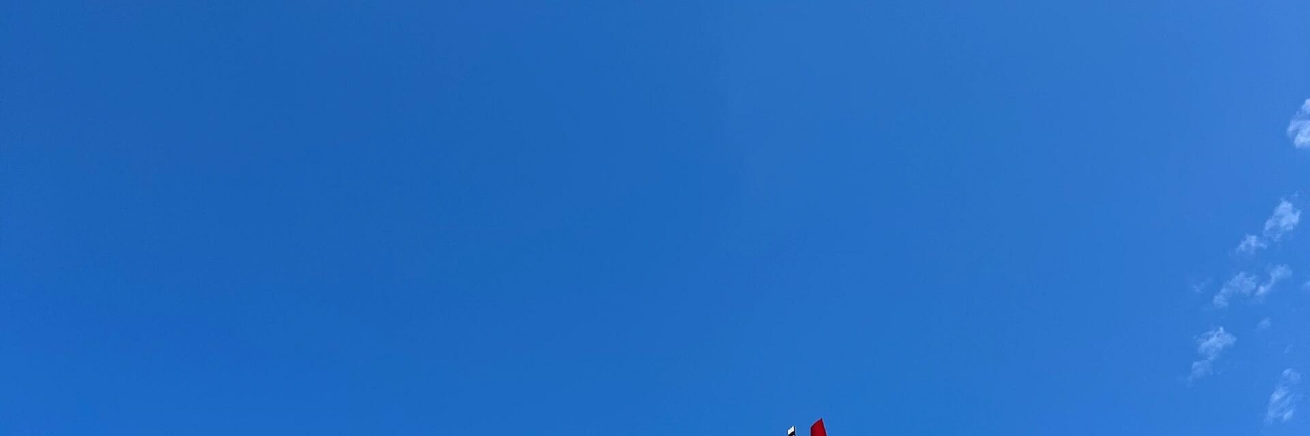 紅色直升機劃破澄澈藍天，在千島湖上空自在翱翔，鮮豔色彩與白雲相映，充滿動感與活力，盡顯空中飛行的自由與熱烈