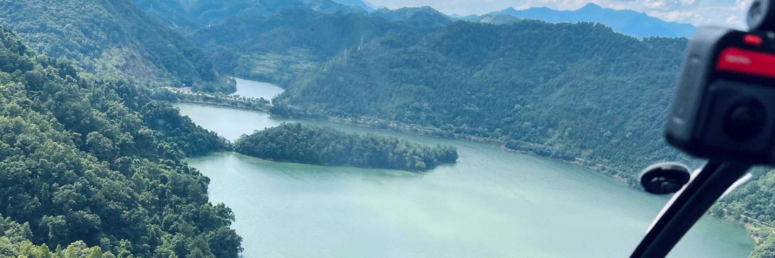 駕駛艙內，指尖輕指窗外千島湖山，澄澈湖水環繞青山，高空視角下的山水肌理清晰可見，沉浸式解鎖高空視野的治癒與震撼