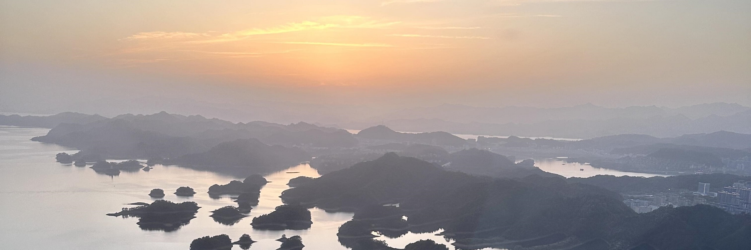 落日餘暉為千島湖鍍上暖橘濾鏡，島群在霞光中暈染出溫柔輪廓，水天相融如流動油畫，靜謐又浪漫，每一幀都是治癒人心的黃昏盛景