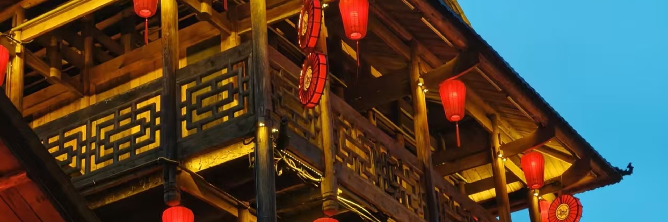 暮色漸濃時，這座三層木樓被紅燈籠與暖黃燈光點亮，層層疊疊的雕花欄杆與木樑在夜色裡格外醒目