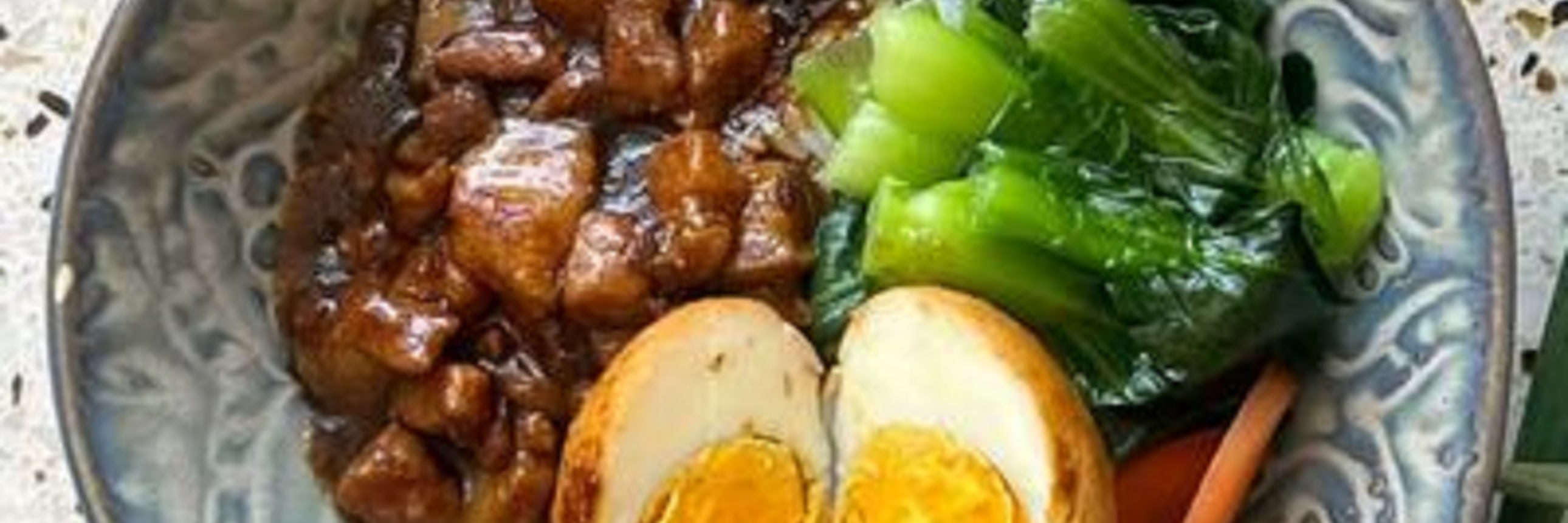 一碗滷肉飯，配溏心蛋、青菜與胡蘿蔔，色澤誘人，家常美味