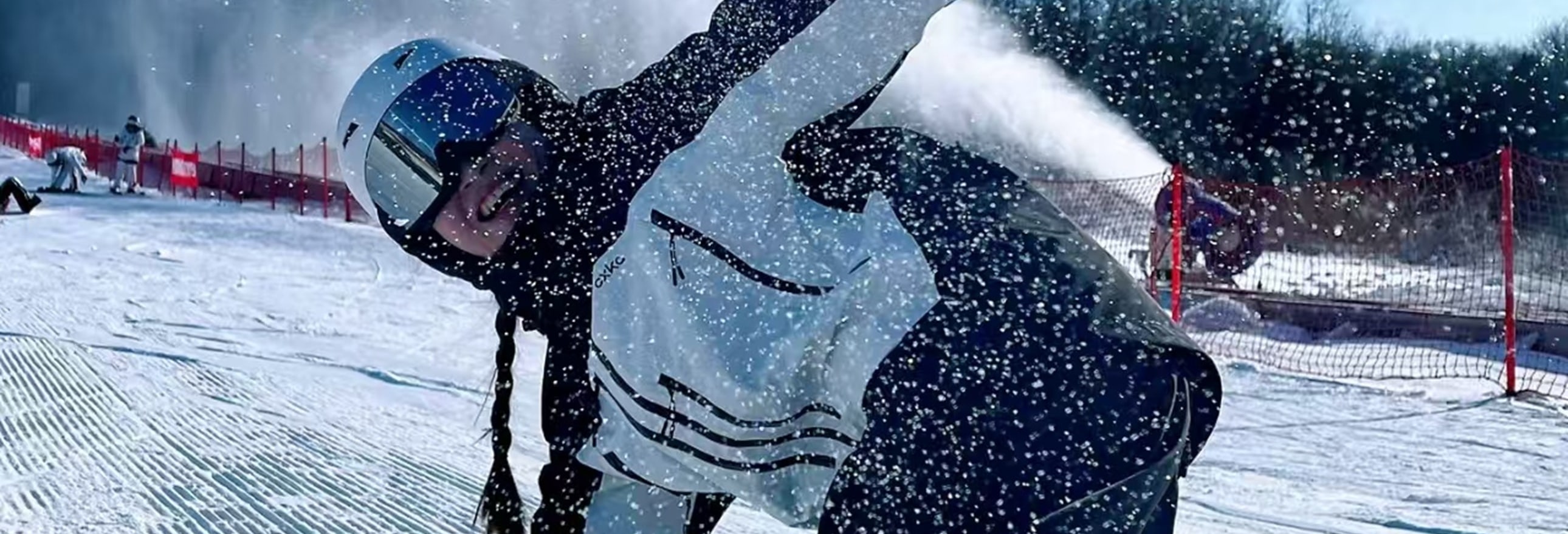 滑雪者大幅傾斜身體，雪霧隨動作揚起，造雪機噴雪襯後景，光影交織間，動感與冬日氛圍拉滿