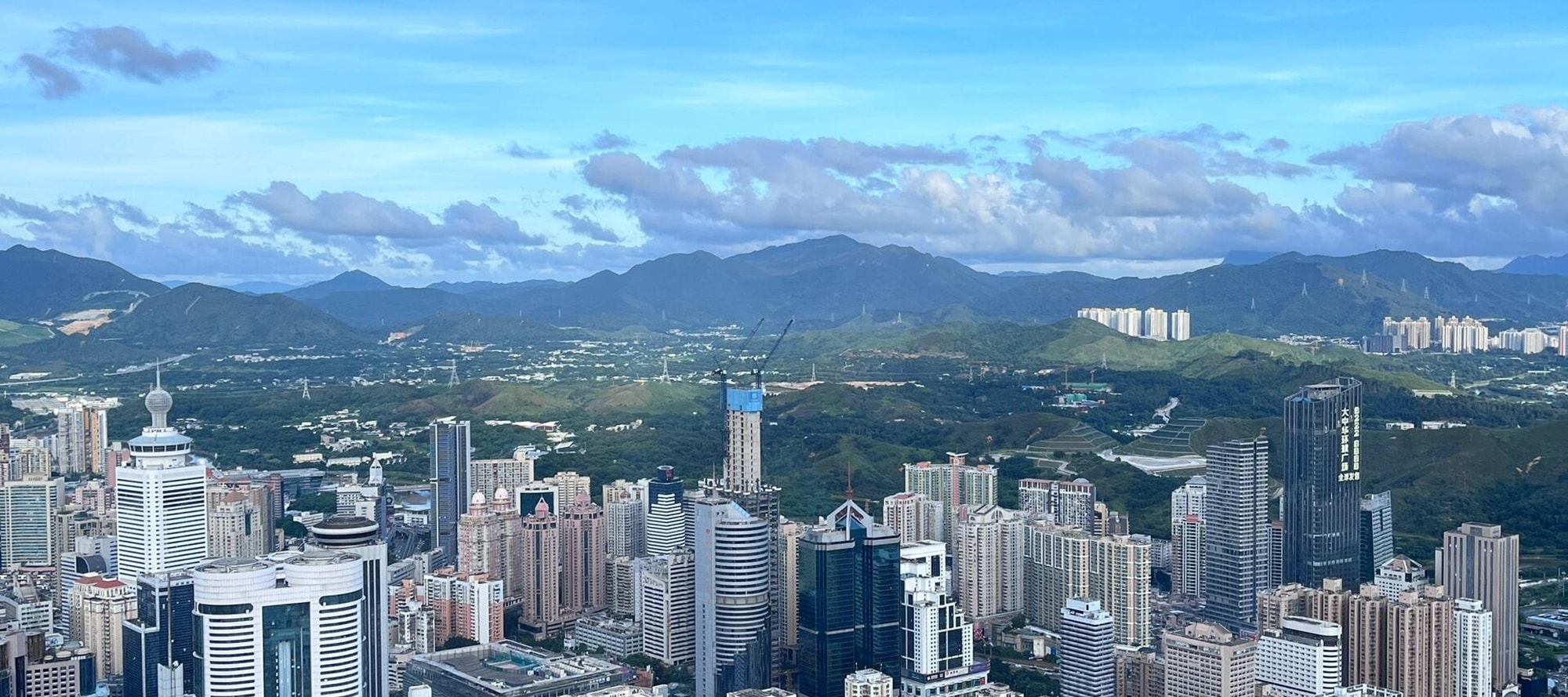 Shenzhen aerial view, blue sky, buildings, and distant mountains in one frame, immersive experience of the beauty of the fusion of city and nature