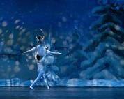 Ballerina in a white tutu lifted overhead by her p