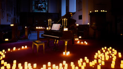 A piano with candles on the floor around it