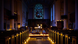 A church aisle leading to a piano, with candles