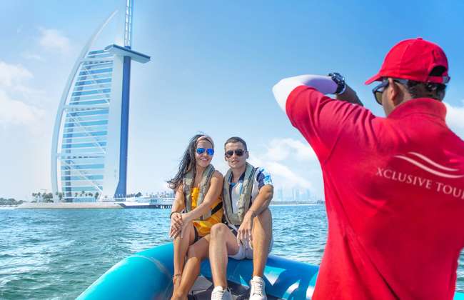 Passengers and crew aboard a speedboat with the Burj Al Arab in the distance.