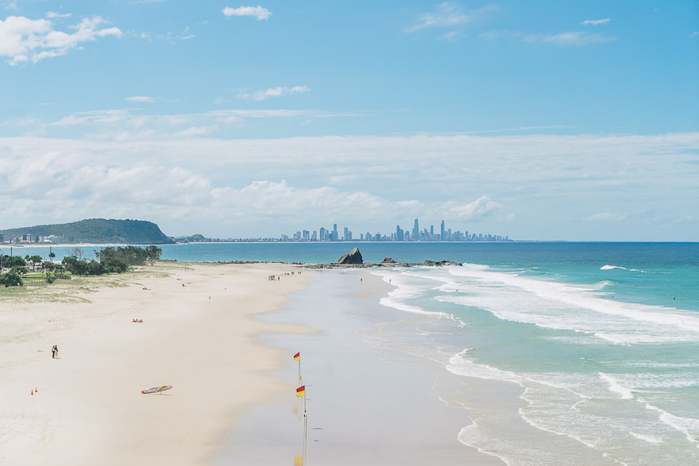 A photo of Currumbin Beach, with the city’s buildings seen from afar