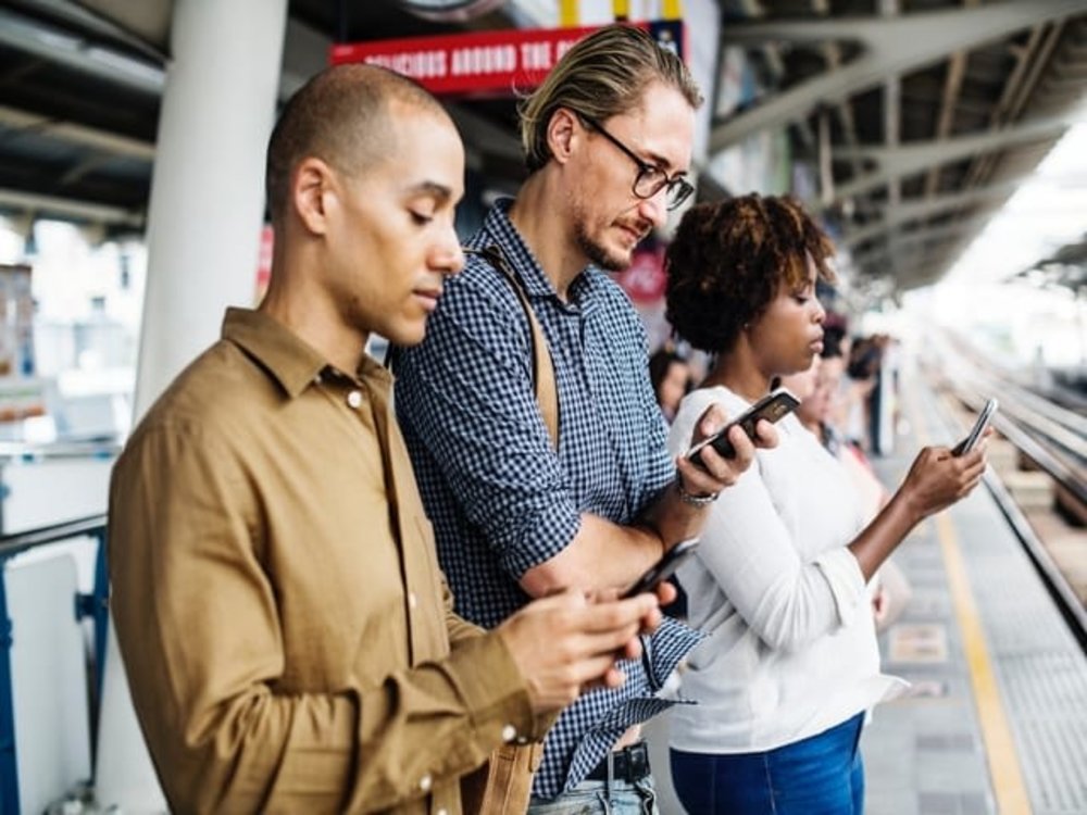 people standing train platform phones mobile distractd