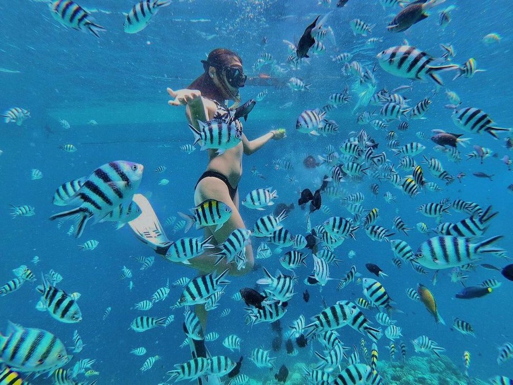 woman playing with fishes in Hilutungan Island
