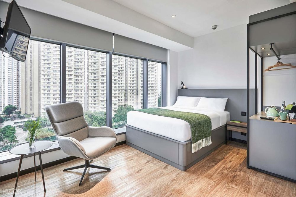 deluxe room with chair and bed overlooking buildings at urbanwood