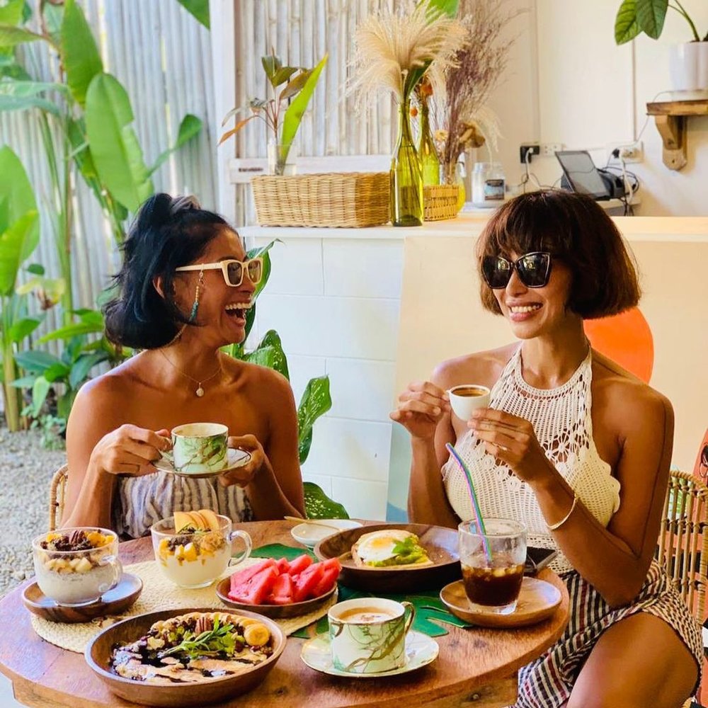 two girls laughing while holding coffee at mauloa siargao cafe