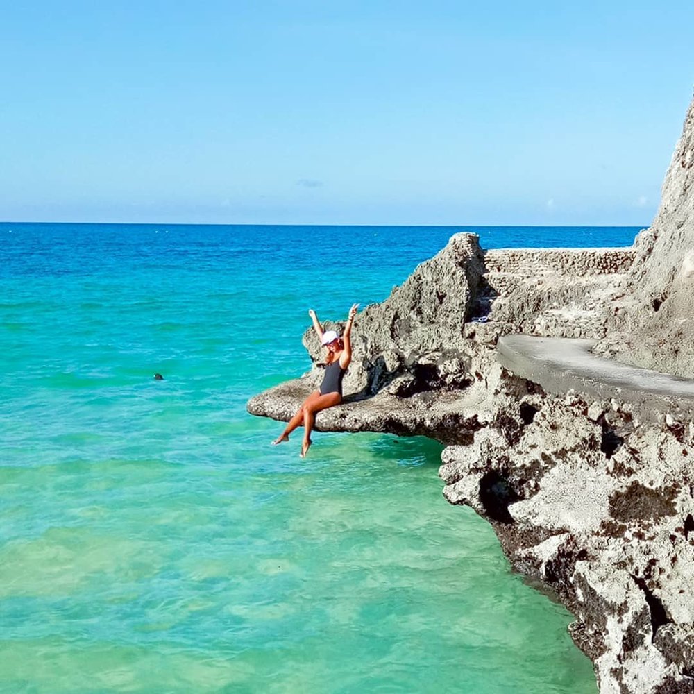 woman sitting on cliff road at diniwid beach boracay