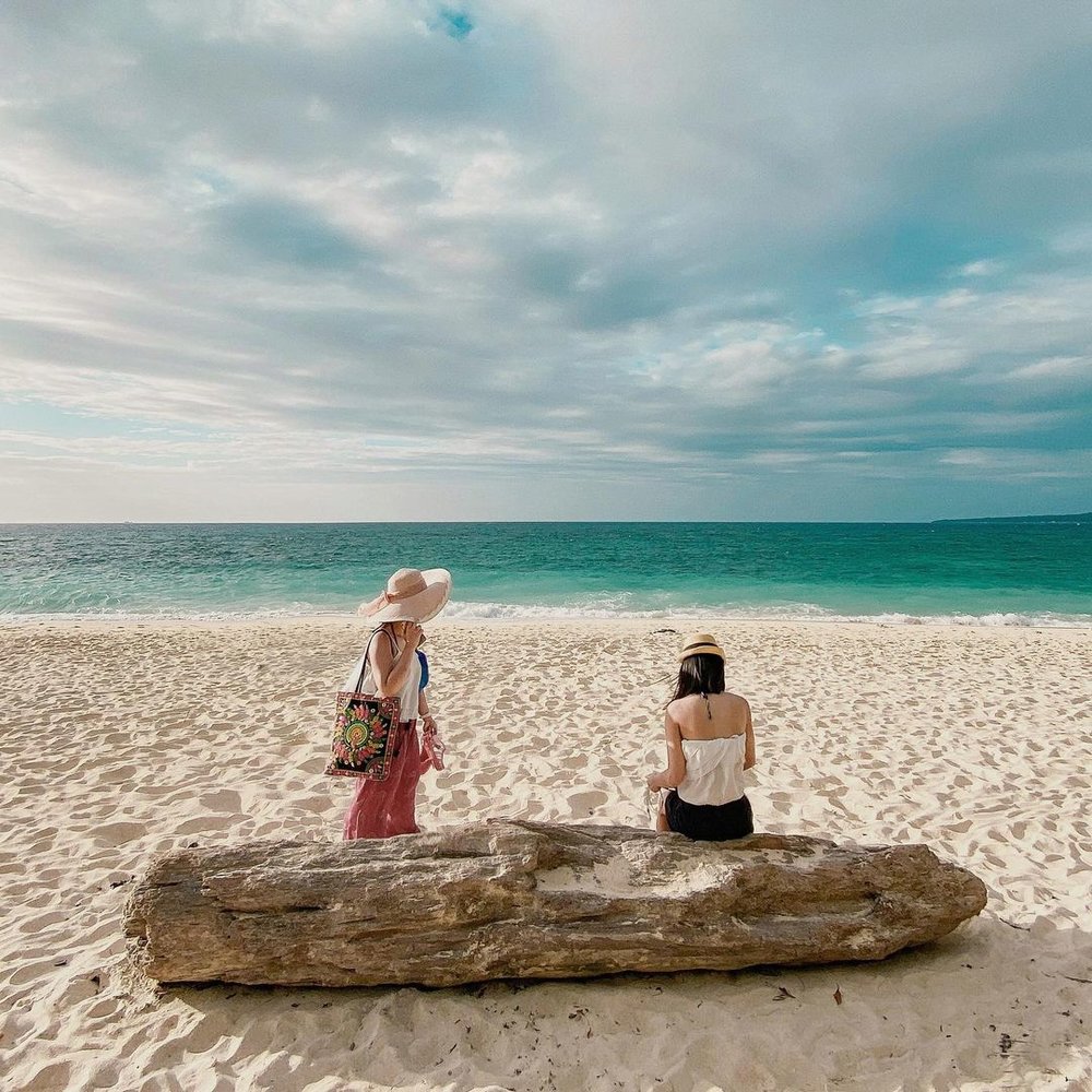 girls sitting on log at puka beach boracay