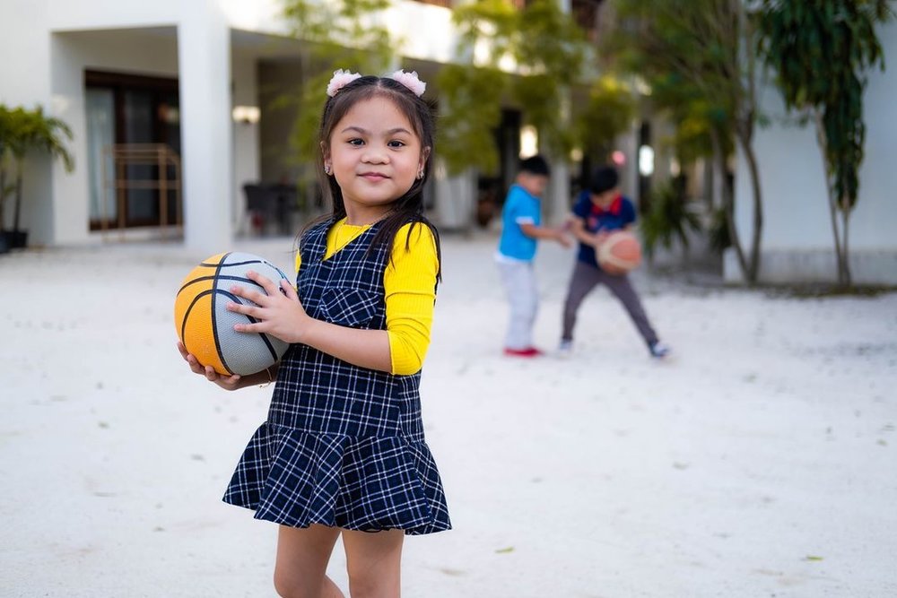 kid holding ball at beach