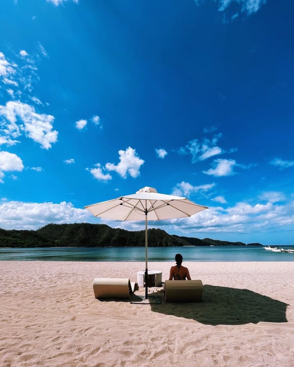 girl at the beach lounging underneath an umbrella
