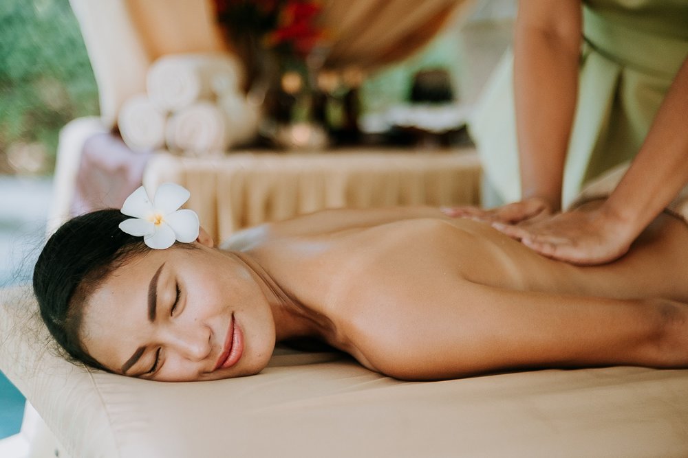 woman with eyes closed smiling while getting a massage