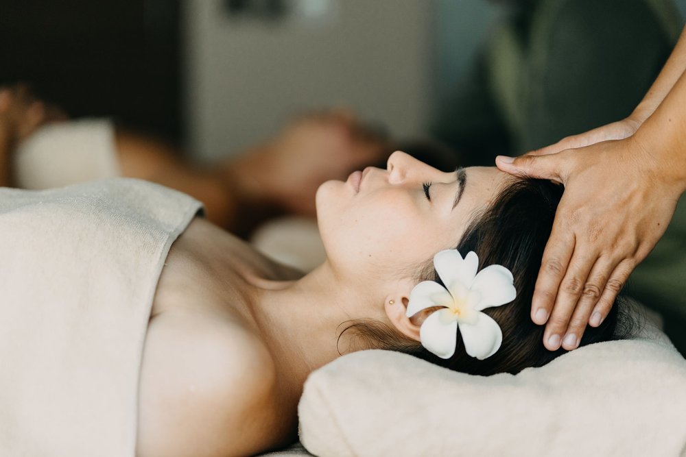 woman with flower in ear getting a head massage