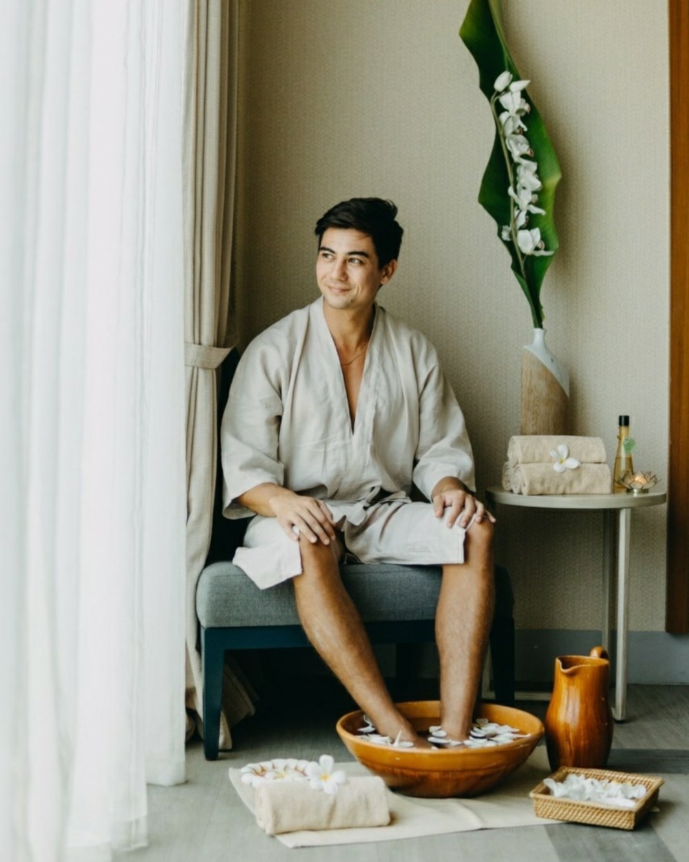 man in spa robe smiling while getting foot spa