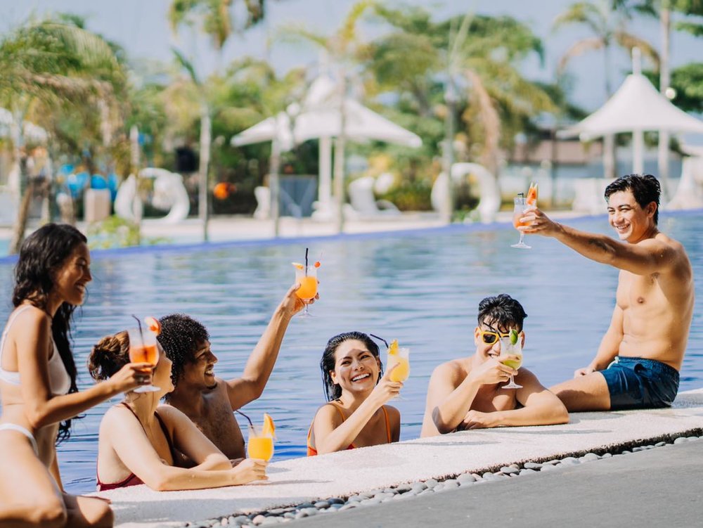 group of friends hanging and drinking by the pool