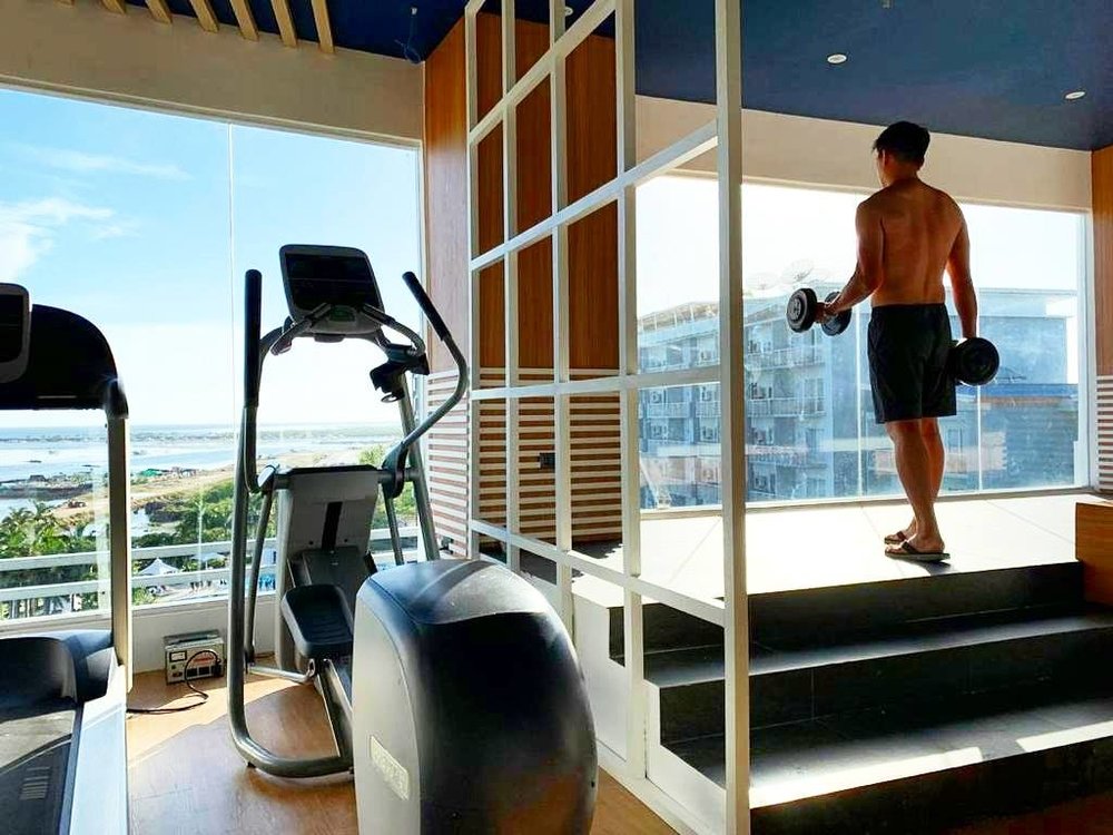 man lifting weights in hotel gym with view