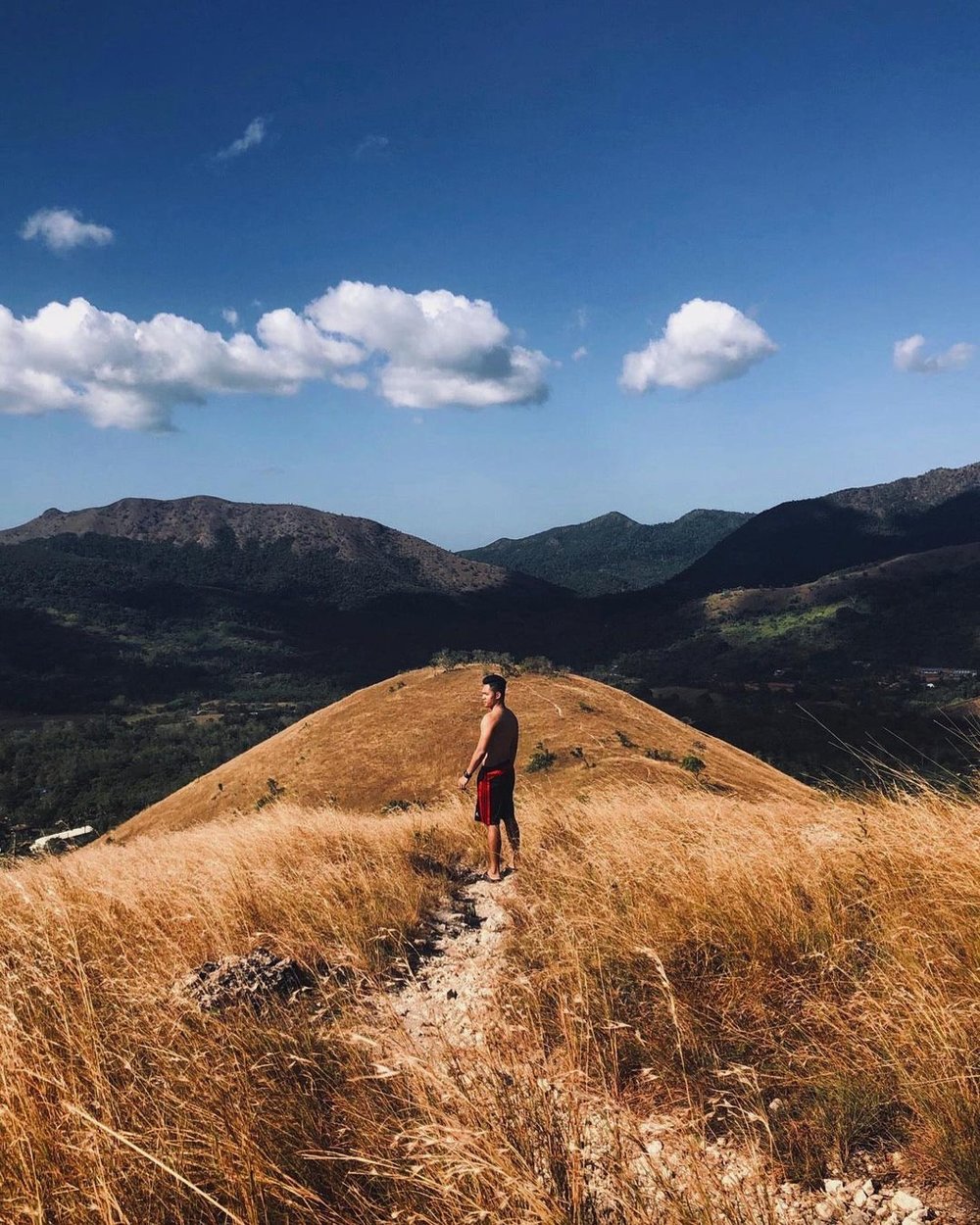 man in the middle of yellow brown grassy hill