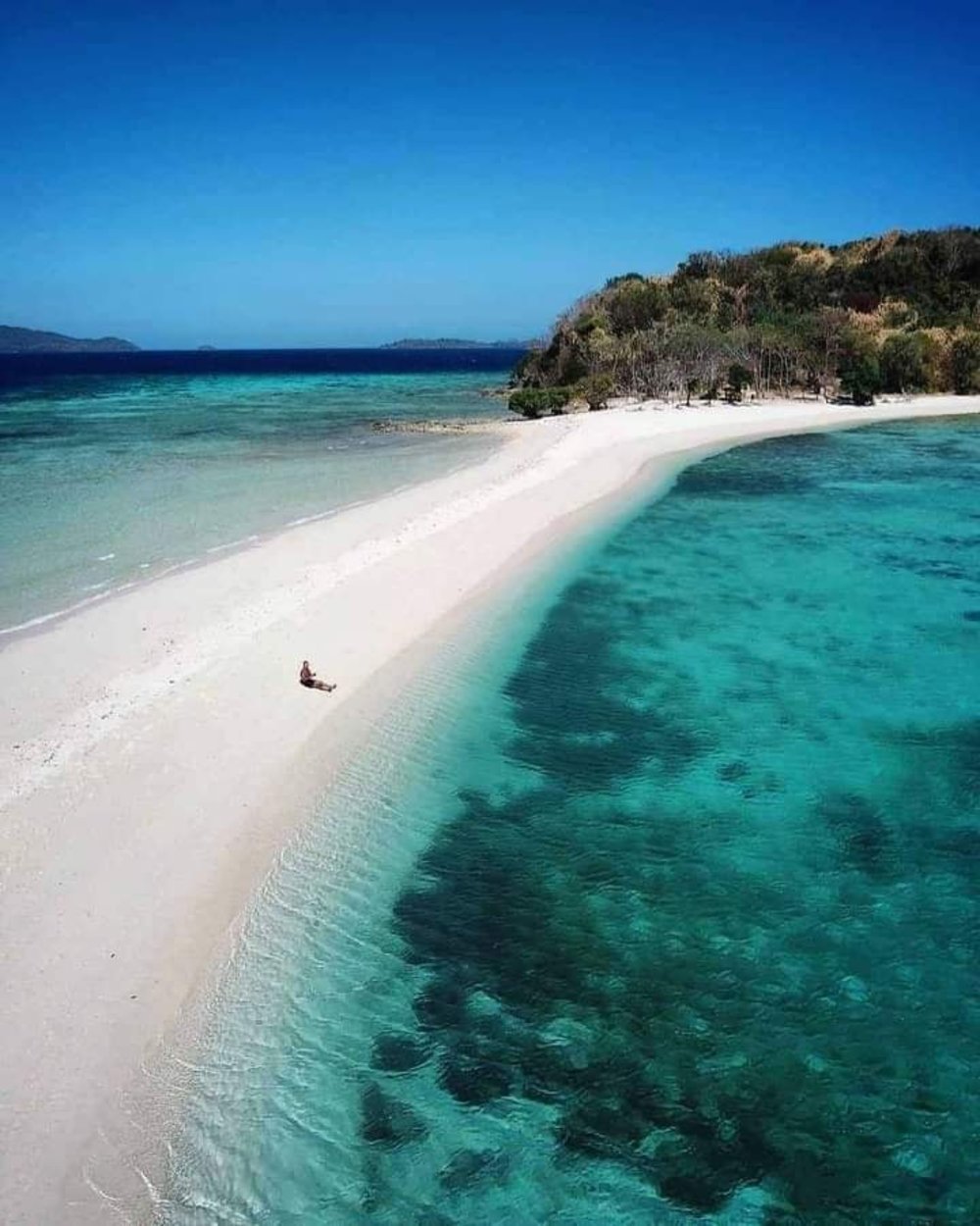 man sitting in white sand bar