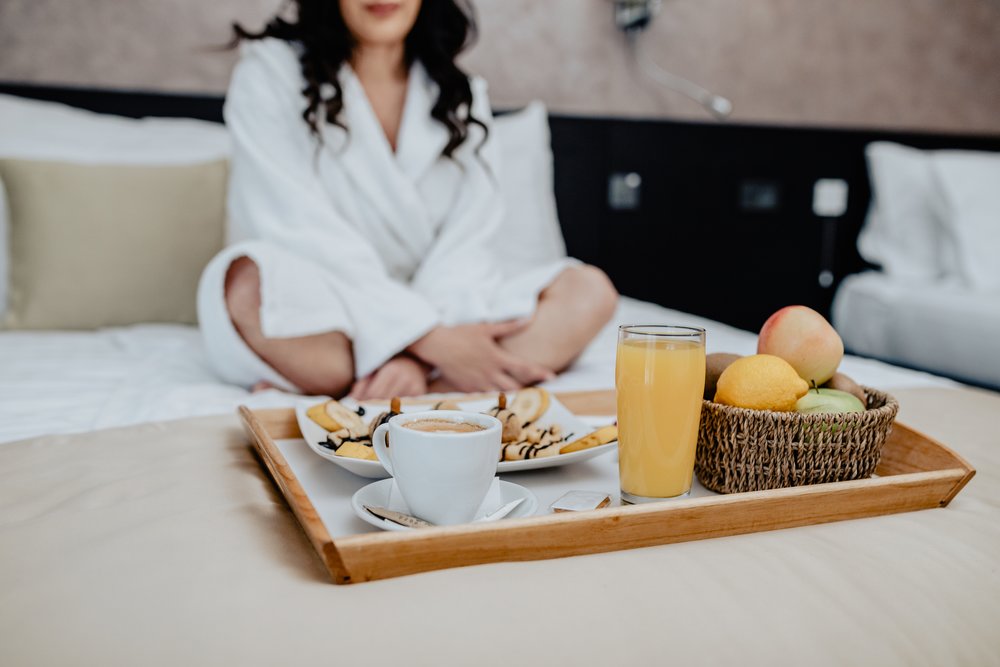 woman in hotel bed enjoying breakfast