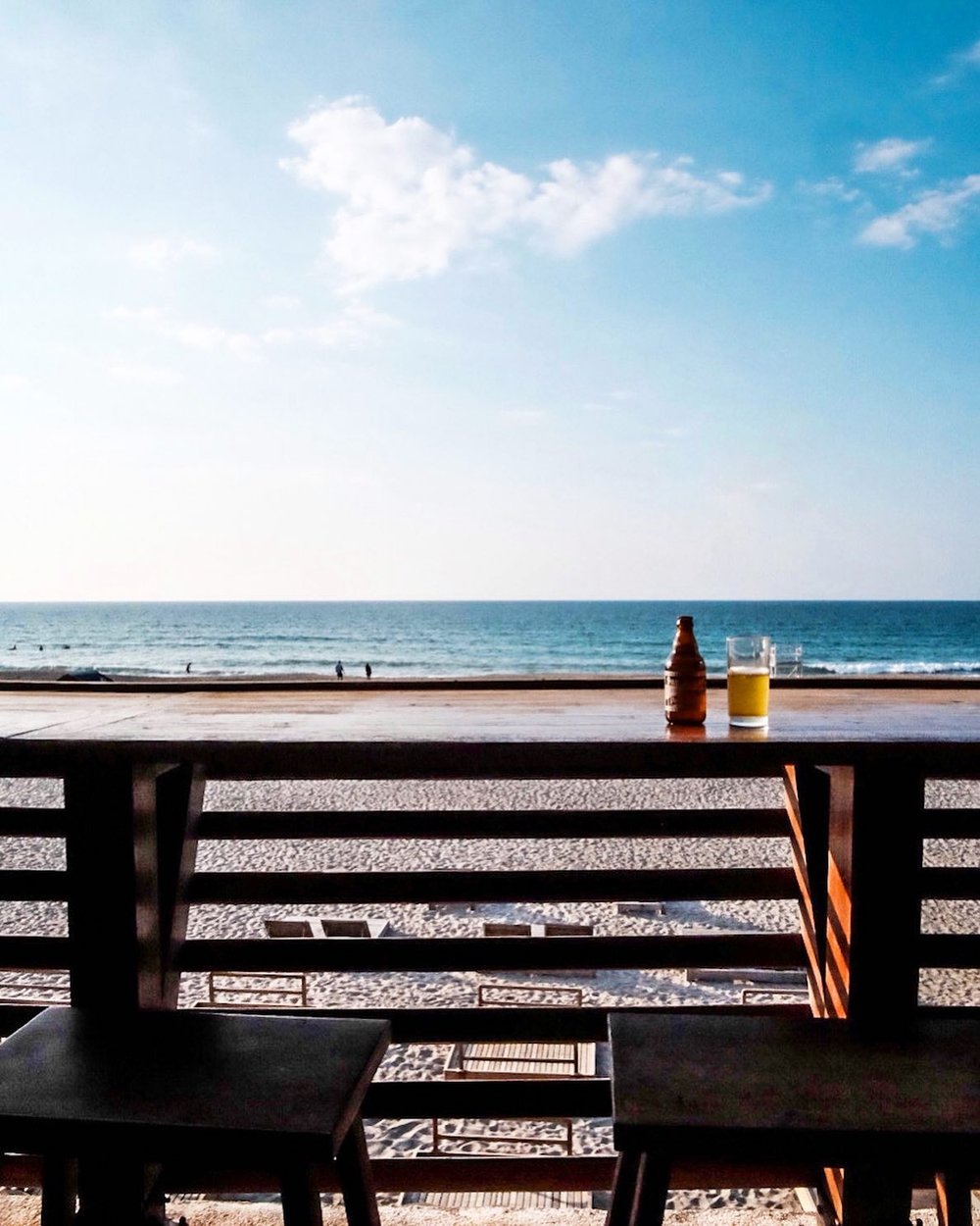 bottle of beer on table overlooking beach