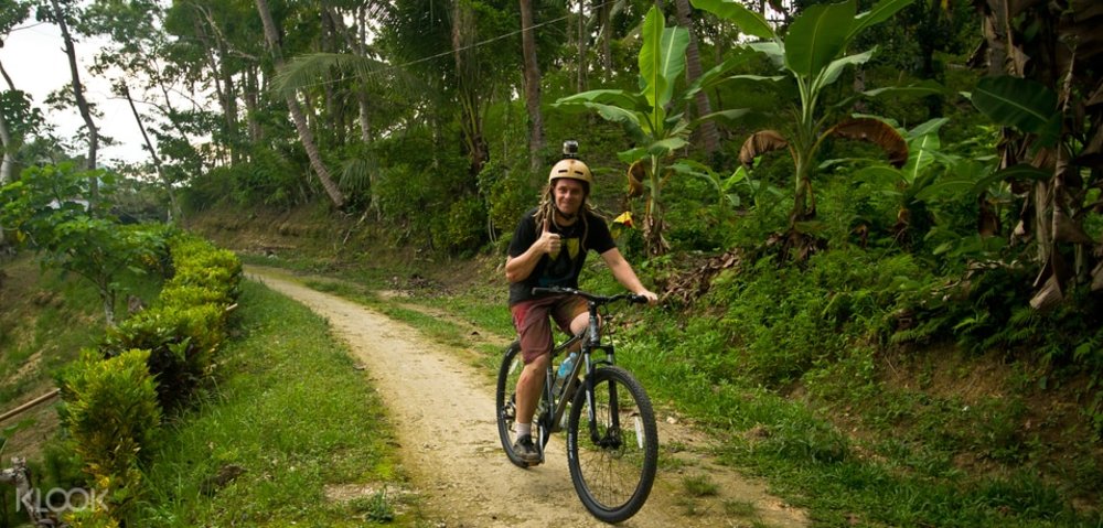 blonde guy doing a thumbs up sign while biking