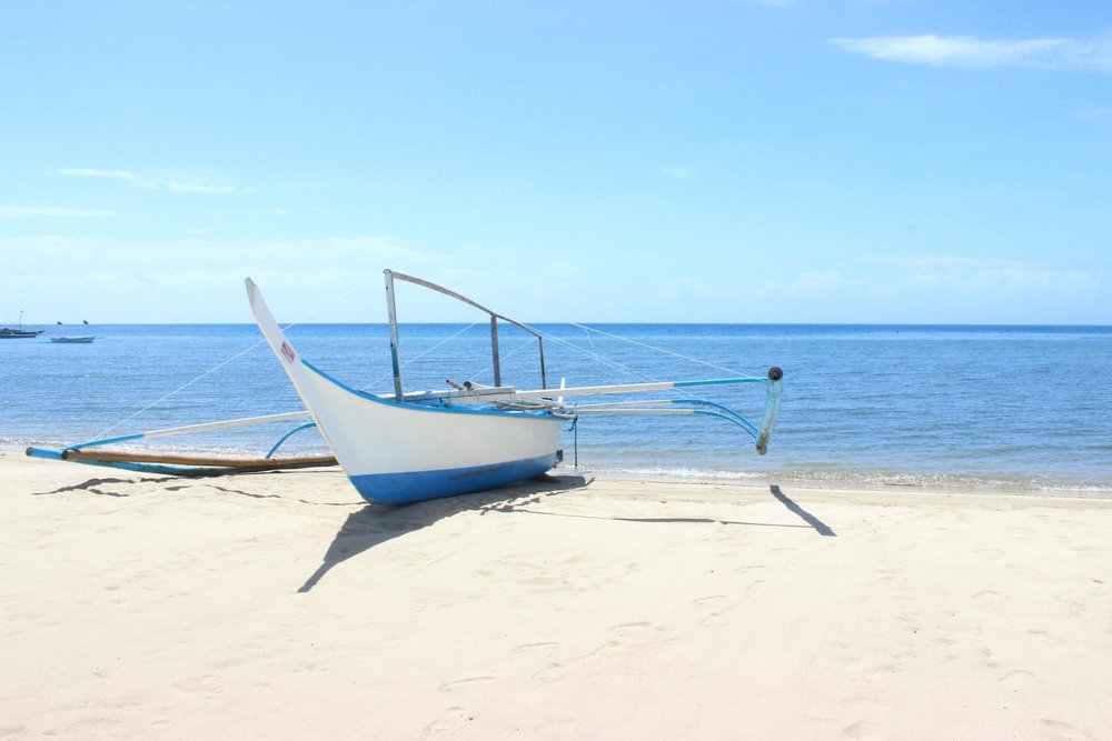 fisherman's boat docked on white sand beach