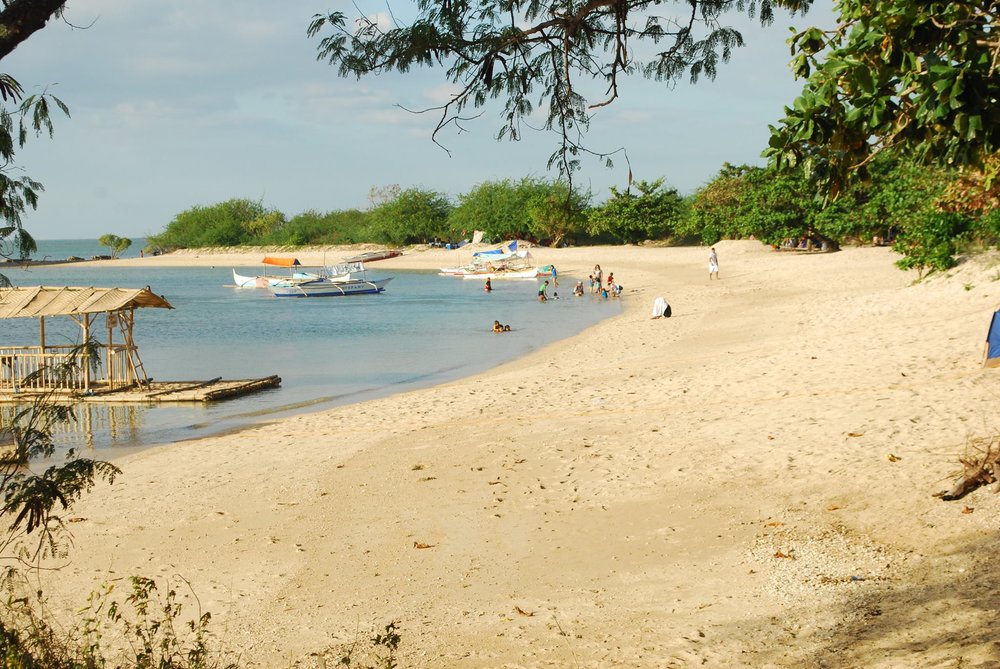 beach shore with boats and people playing
