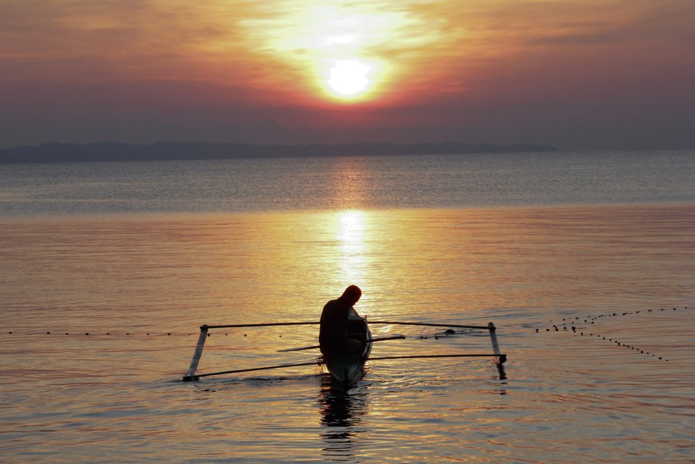 man on boat overlooking sunset