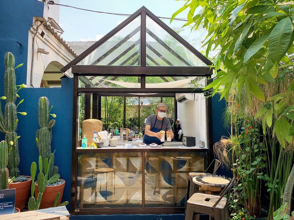 male barista serving coffee is glass house